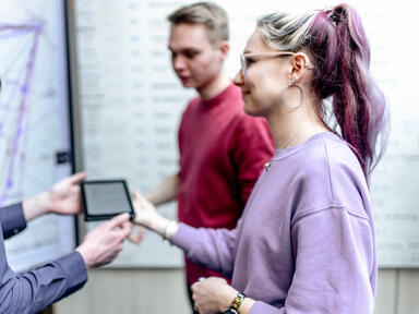 Wittler Mitarbeiterin und Mitarbeiter (Industriekaufleute) vor Großformat-Display mit Tourenplanung